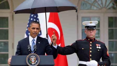 President Barack Obama speaks under an umbrella held by a Marine as a light rain falls during a news conference with Turkish Prime Minister Recep Tayyip Erdogan, Thursday, May 16, 2013, in the Rose Garden of the White House. (AP Photo/Jacquelyn Martin)