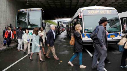 Metro North employees, in orange vests, help transfer westbound commuters at the transportation center in Bridgeport, Ct., to shuttle buses Monday, May 20, 2013. The commuters had arrived from New Haven by train and were being bused to Stamford, Ct., where rail service to New York was available. A train collision on Friday injured 72 people and disrupted rail service into New York City. (AP Photo/Mark Lennihan)