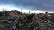 An American flag blows in the wind at sunrise atop the rubble of a destroyed home a day after a tornado moved through Moore, Okla., Tuesday, May 21, 2013. The monstrous tornado roared through the Oklahoma City suburb Monday, flattening entire neighborhoods and destroying an elementary school with a direct blow as children and teachers huddled against winds up to 200 mph. (AP Photo/Brennan Linsley)
