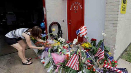 Shannon Neira places flowers at a makeshift memorial at Houston Fire Station 51, Saturday, June 1, 2013, in Houston. Four firefighters searching for people they thought might be trapped in a blazing Houston motel and restaurant Friday were killed when part of the structure collapsed and ensnared them, authorities said. (AP Photo/David J. Phillip)