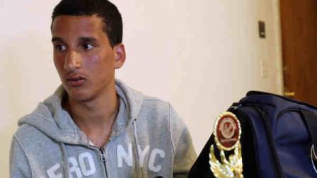 FILE - In this April 18, 2013 file photo, Salah Eddin Barhoum sits in his apartment in Revere, Mass., with one of the trophies he won in an athletic competition, and the bag he was carrying on Monday near the finish line of the Boston Marathon. Barhoum, one of two men whose photograph appeared threeon the front page of the New York Post in connection with the Boston Marathon bombings, filed a libel lawsuit against the Post Wednesday, June 5, 2013. (AP Photo/Rodrique Ngowi, File)