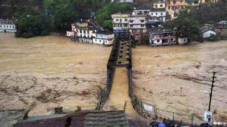 People gather to watch a bridge submerged in the flooded water of the River Ganges in Rudraprayag, in northern Indian state of Uttarakhand, India, Tuesday, June 18, 2013. Torrential rain and floods washed away buildings and roads, killing at least 23 people in the northern Indian state of Uttarakhand, officials said Monday. (AP Photo)