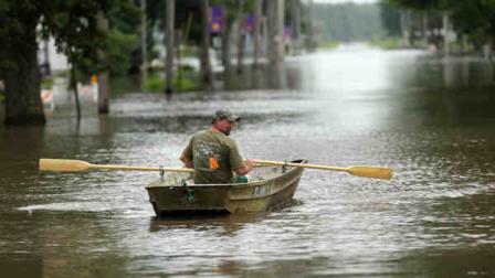 Jim Johnson rows his boat down Main Street, Tuesday, June 25, 2013, in New Hartford, Iowa. Hundreds of residents obeyed an order to evacuate their homes in this northeast Iowa town Tuesday before floodwaters from a rising creek could strand them. (AP Photo/Charlie Neibergall)