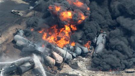 Smoke rises from railway cars that were carrying crude oil after derailing in downtown Lac Megantic, Que., Saturday, July 6, 2013. A large swath of Lac Megantic was destroyed Saturday after a train carrying crude oil derailed, sparking several explosions and forcing the evacuation of up to 1,000 people. (AP Photo/The Canadian Press, Paul Chiasson)