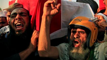 Supporters of Egypts ousted President Mohammed Morsi chant angry slogans as they carry a coffin covered with the national flag, of a man killed after Egyptian troops opened fire on mostly Islamist protesters marching on a Republican Guard headquarters Friday, in Cairo, Saturday, July 6, 2013. (AP Photo/Khalil Hamra)