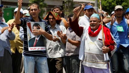 Supporters of Egypts ousted President Mohammed Morsi chant slogans at a sit-in in Nasser City, suburb of Cairo, Egypt, Sunday, July 7, 2013. Egypts new president moved to assert his authority and regain control of the streets Saturday even as his Islamist opponents declared his powers illegitimate and issued blood oaths to reinstate Mohammed Morsi, whose ouster by the military has led to dueling protests and deadly street battles between rival sides. The Arabic on the poster of Morsi reads, No alternative to legitimacy. (AP Photo/Paul Schemm)