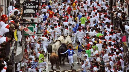 Runners make their way through the street with El Pilar fighting bulls watched by people from their balconies during the running of the bulls at the San Fermin festival, in Pamplona, Spain, Friday, July 12, 2013. Revelers from around the world arrive to Pamplona every year to take part in some of the eight days of the running of the bulls. (AP Photo/Alvaro Barrientos)