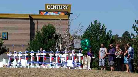 People visit 12 crosses erected in memory of the 12 people who were killed in the Aurora theater shooting on a hill across the street from the theater in Aurora, Colo., on Saturday, July 20, 2013. Coloradans marked the one-year anniversary of the Aurora movie theater massacre with a city-sponsored Day of Remembrance. (AP Photo/Ed Andrieski)