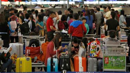 Passengers whose travel plans were affected by Typhoon Usagi wait at airline counters at Hong Kongs international airport Monday, Sept. 23, 2013. (AP Photo/Vincent Yu)