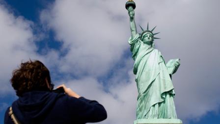 A tourist photographs the Statue of Liberty in New York Harbor, Sunday, Oct. 13, 2013, in New York. The Statue of Liberty reopened to the public after the state of New York agreed to shoulder the costs of running the site during the partial federal government shutdown. (AP Photo/John Minchillo)