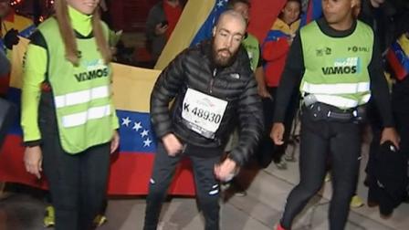 This photo from video provided by Ken Herzlich of Embargo Chicago shows Maickel Melamed, 38, center, of Venezuela, who has muscular dystrophy, nearing the finish line early Monday, Oct. 14, 2013, to be the last runner to finish the Chicago Marathon _ nearly 17 hours after he started the race. About 100 people cheered him on as he finished. Melamed started running marathons two years ago and has competed in marathons in Berlin and New York City. His time for the Chicago Marathon was 16 hours and 46 minutes. (AP Photo/Courtesy of Ken Herlich, Embargo Chicago)