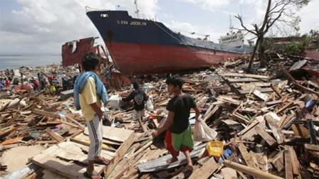 Residents walk beside a large ship that was washed ashore by strong waves caused by Typhoon Haiyan in Tacloban city, Leyte province central Philippines on Sunday, Nov. 10, 2013. Typhoon Haiyan, one of the strongest storms on record, slammed into six central Philippine islands on Friday leaving a wide swath of destruction and hundreds of people dead. (AP Photo/Aaron Favila)