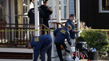 Law enforcement officials remove protective slippers outside a two-family home in Arlington, Mass., where four people were found dead on Monday, Nov. 18, 2013. (AP Photo/Steven Senne)