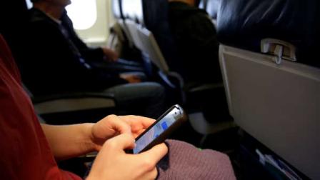 A passenger check her cell phone before a flight, Thursday, Oct. 31, 2013, in Boston. (AP Photo/Matt Slocum)