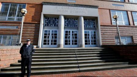 FILE - In this file photo from Jan. 9, 2013, a security guard stands near the entrance to Steubenville High School in Steubenville, Ohio. (AP Photo/Keith Srakocic, File)
