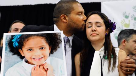 FILE - In this Jan. 14, 2013 file photo, Jimmy Greene, left, kisses his wife Nelba Marquez-Greene while holding a portrait of their daughter, Sandy Hook Elementary School shooting victim Ana Marquez-Greene, at a news conference at Edmond Town Hall in Newtown, Conn. Ana Marquez-Greene was one of 26 people killed when Adam Lanza opened fire inside the school on Dec. 14, 2012, in Newtown, Conn. (AP Photo/Jessica Hill, File)