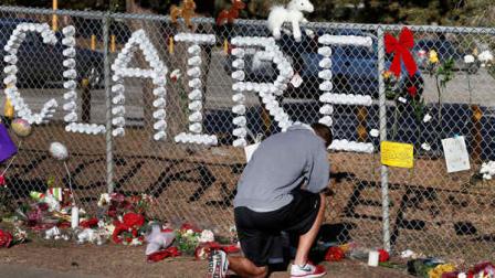 Parker Semin, a 2011 Arapahoe High School graduate, prays at a makeshift memorial bearing the name of wounded student Claire Davis, who was shot by a classmate during school three days earlier in an attack, in front of Arapahoe High School in Centennial, Colo., Monday, Dec. 16, 2013. (AP Photo/Brennan Linsley)