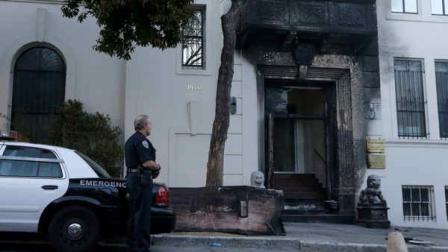A San Francisco Police officer stands outside of the damaged entrance to the Chinese Consulate in San Francisco on Thursday, Jan. 2, 2014. The consulate said in a notice on its website that a person came out of a van parked outside the compound Wednesday night with two buckets of gasoline, poured the fuel on the front of the consulate building and set it on fire. (AP Photo/Jeff Chiu)