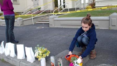 Amanda Enemark lays flowers at an impromptu shrine while Lauire Lynch prays Thursday, Jan. 2, 2014, outside St. Bernard Catholic Church rectory in Eureka, Calif., where Fr. Eric Freed was found slain on New Years Day. Police arrested a man Thursday in the slaying. He was identified as Gary Lee Bullock, 43, of Redway, Calif. (AP Photo/Jeff Barnard)