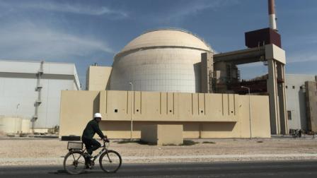 FILE - In this Oct. 26, 2010 file photo, a worker rides a bicycle in front of the reactor building of the Bushehr nuclear power plant, just outside the southern city of Bushehr. Iran and six world powers have agreed on how to implement a nuclear deal struck in November, with its terms starting from Jan. 20, officials announced Sunday. (AP Photo/Mehr News Agency, Majid Asgaripour, File)