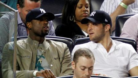 Miami Heats Dwayne Wade, left, sits beside New York Jets quarterback Tim Tebow during the New York Yankees baseball game against the Los Angeles Angels at Yankee Stadium in New York, Sunday, April 15, 2012. (AP Photo/Kathy Willens)
