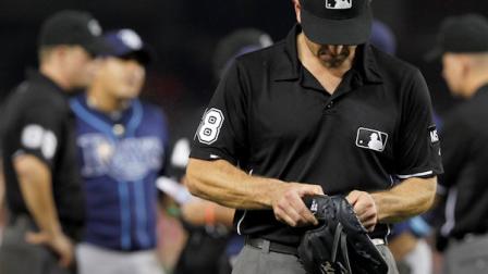 Umpire Chris Cuccione leaves with the glove of Tampa Bay Rays relief pitcher Joel Peralta during the eighth inning of a baseball game against the Washington Nationals on Tuesday, June 19, 2012, in Washington. Peralta was ejected in the eighth inning for having a foreign substance on his glove. (AP Photo/Alex Brandon)