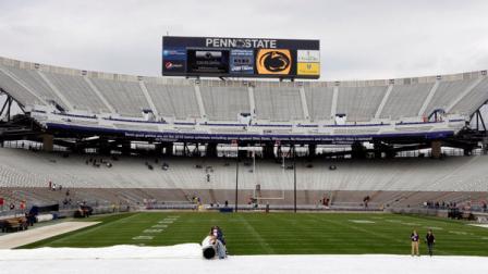 Workers roll off the tarp covering the playing surface at Beaver Stadium in preparation for the annual spring Blue White NCAA football spring scrimmage on Saturday, April 21, 2012, in State College, Pa.