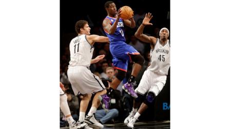 Philadelphia 76ers Jrue Holiday, center, looks to pass past Brooklyn Nets Brook Lopez, left, and Gerald Wallace during the first half of an NBA basketball game at the Barclays Center Sunday, Dec. 23, 2012 in New York. (AP Photo/Seth Wenig)