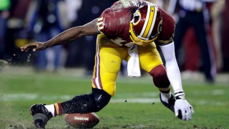 Washington Redskins quarterback Robert Griffin III twists his knees as he reaches for the loose ball after a low snap during the second half of an NFL wild card playoff football game against the Seattle Seahawks in Landover, Md., Sunday, Jan. 6, 2013. (AP Photo/Matt Slocum)