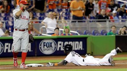 Miami Marlins Adeiny Hechavarria (3) slides safely into third base after batting a triple as Philadelphia Phillies Freddy Galvis (13) awaits the late throw against during the fifth inning of a baseball game in Miami, Saturday, April 13, 2013. (AP Photo/Alan Diaz)