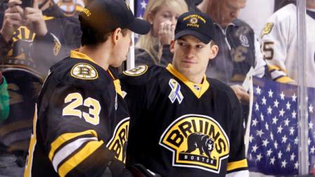 Wearing hats from local law enforcement agencies, Boston Bruins defenseman Andrew Ference, right, talks with teammate Chris Kelly (23) before an NHL hockey game against the Pittsburgh Penguins, Saturday, April 20, 2013, in Boston. (AP Photo/Mary Schwalm)