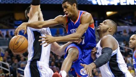 Philadelphia 76ers Hollis Thompson, center, passes the ball as he gets caught between Orlando Magics Nikola Vucevic, left, of Montenegro, and Glen Davis, right, during the first half of an NBA basketball game in Orlando, Fla., Wednesday, Nov. 27, 2013.(AP Photo/John Raoux)