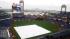 A fan huddles under an umbrealla as the infield...