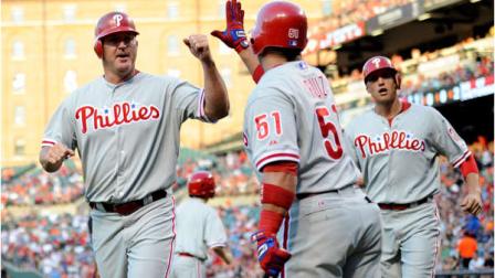 Philadelphia Phillies Jim Thome, left, gets a high-five from teammate Carlos Ruiz (51) as he and Hunter Pence, right, scored on a double by Shane Victorino during the second inning of a baseball game against the Baltimore Orioles, Friday, June 8, 2012, in Baltimore. (AP Photo/Nick Wass)