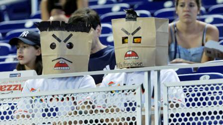A pair of baseball fans wear bags on their heads at the start of a baseball game between the Miami Marlins and the Philadelphia Phillies, Wednesday, Aug. 15, 2012 in Miami. (AP Photo/Wilfredo Lee)
