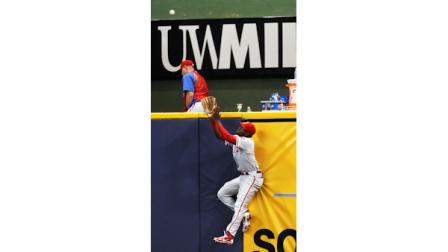 Philadelphia Phillies Domonic Brown, right, leaps up the right field wall but was not able to make a play on Milwaukee Brewers Corey Hart grand slam home run off of Josh Lindblom during the eighth inning of a baseball game, Thursday, Aug. 16, 2012, in Milwaukee. (AP Photo/Tom Lynn)