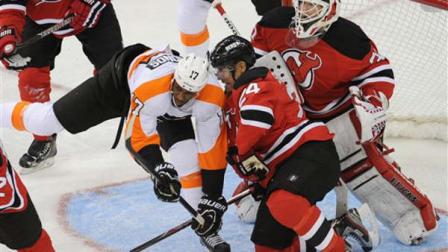 New Jersey Devils Bryce Salvadore (24) checks Philadelphia Flyers Wayne Simmonds (17) in front of Devils goaltender Martin Brodeur during the second period of an NHL hockey game Friday, Feb. 15, 2013, in Newark, N.J. (AP Photo/Bill Kostroun)