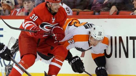 Carolina Hurricanes Patrick Dwyer (39) checks Philadelphia Flyers Michael Raffl (12), of Austria, during the first period of an NHL hockey game in Raleigh, N.C., Tuesday, Nov. 5, 2013. (AP Photo/Gerry Broome)