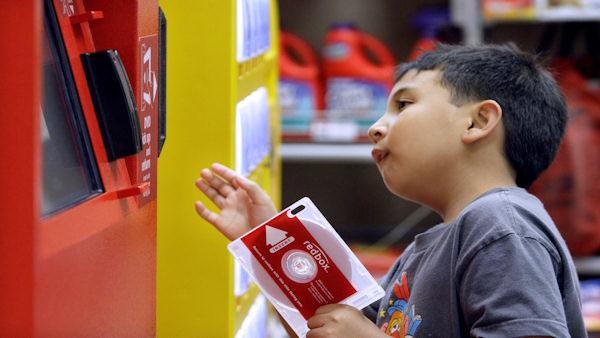 In this photo made Tuesday, June 9, 2009, Sydney Ragpala, 7, waits for a DVD to pop out of a Redbox rental unit in a north Seattle grocery store. (AP Photo/Elaine Thompson)