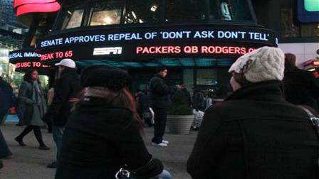 Cassandra Melnikow, foreground left, and her sister Victoria Melnikow, right, sit in New Yorks Times Square as news of the Senate approving the repeal of Dont Ask Dont Tell is displayed outside ABC Televisions Times Square studios Saturday Dec. 18, 2010. (AP Photo/Tina Fineberg)