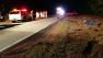 The red pickup truck rolled over in the shoulder of the road.