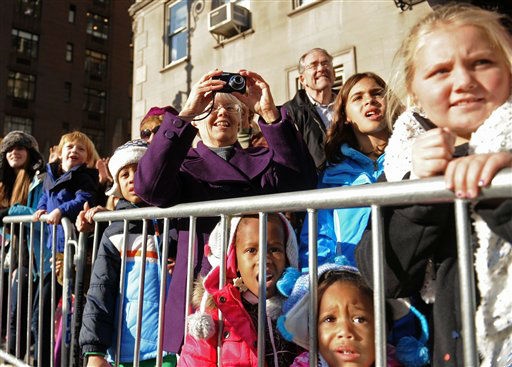 Spectators line the sidewalk as balloons and...