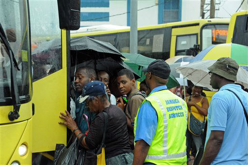 Commuters board a bus as rain brought by the...
