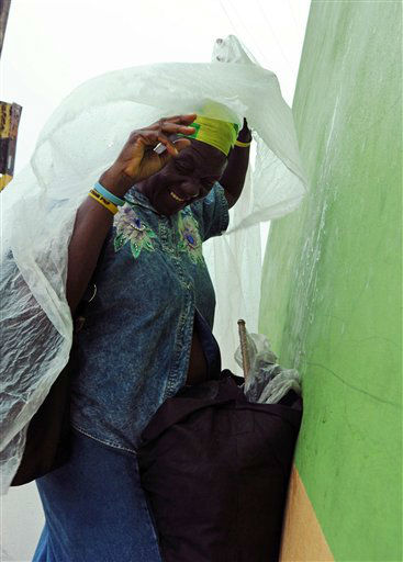 Pauline Daley covers herself as rain brought by...