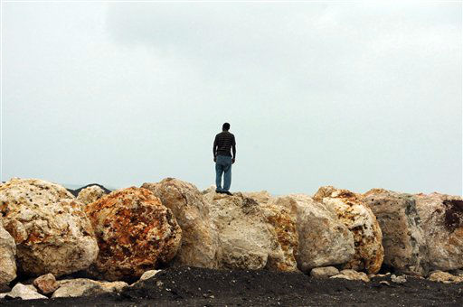 A man stands on boulders placed as a barrier to...