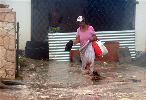 A woman wades through flood water brought by...