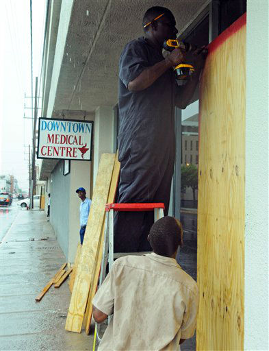 Garth Malcolm, left, covers with plywood a primary health center as rain brought by the outer bands of Tropical Storm Sandy falls in Kingston, Jamaica, Tuesday, Oct. 23, 2012.