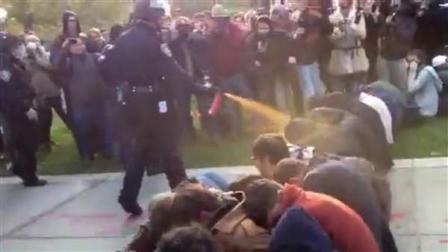 In this image made from video, a police officer uses pepper spray as he walks down a line of Occupy demonstrators sitting on the ground at the University of California, Davis on Friday, Nov. 18, 2011.