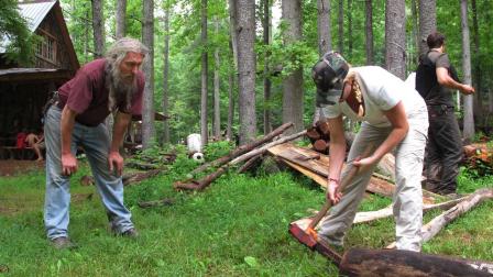Eustace Conway, left, offers encouragement as a camper hammers a wedge into a log at his Turtle Island Preserve in Triplett, N.C., on Thursday, June 27, 2013.