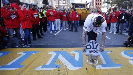 Boston Red Soxs Jonny Gomes places the championship trophy and a Red Sox baseball jersey at the Boston Marathon Finish Line during a pause in their World Series victory rolling rally in Boston
